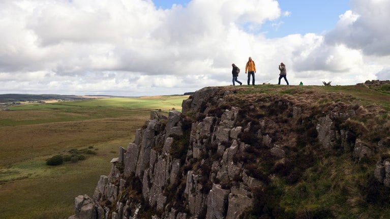 Visitors admiring the view on their walk along the footpath at Hadrian's Wall and Housesteads Fort, Northumberland